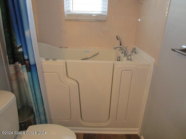 bathroom featuring hardwood / wood-style flooring, toilet, and independent shower and bath