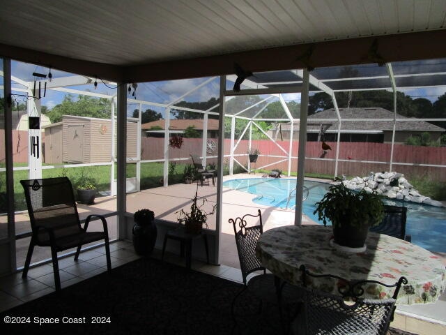 view of swimming pool with a storage unit, a patio area, and a lanai