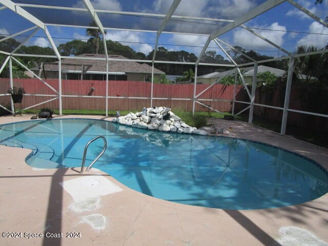 view of pool featuring glass enclosure