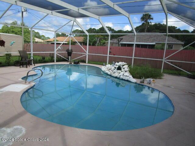 view of swimming pool with glass enclosure and a patio