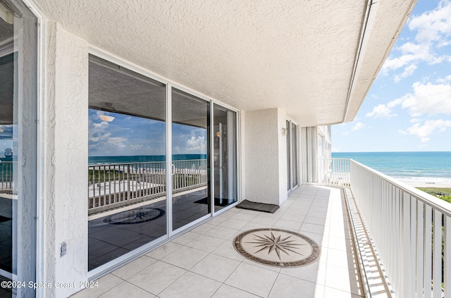 balcony with a water view and a view of the beach