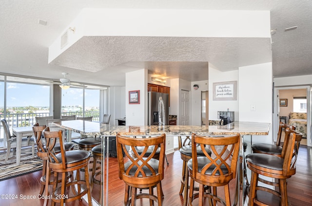 kitchen with stainless steel refrigerator with ice dispenser, a textured ceiling, kitchen peninsula, and dark hardwood / wood-style floors