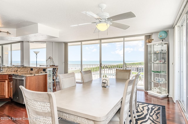 dining room featuring a water view, ceiling fan, dark hardwood / wood-style flooring, and a textured ceiling