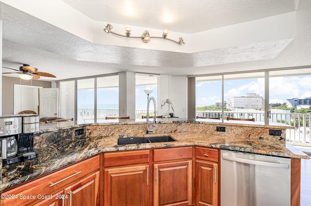 kitchen featuring a textured ceiling, stainless steel dishwasher, ceiling fan, and dark stone counters