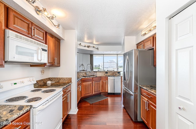 kitchen with stone countertops, a textured ceiling, sink, dark hardwood / wood-style floors, and appliances with stainless steel finishes