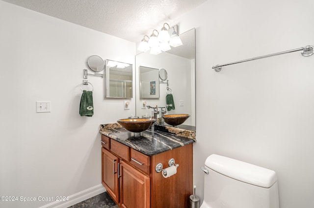 bathroom featuring a textured ceiling, vanity, and toilet