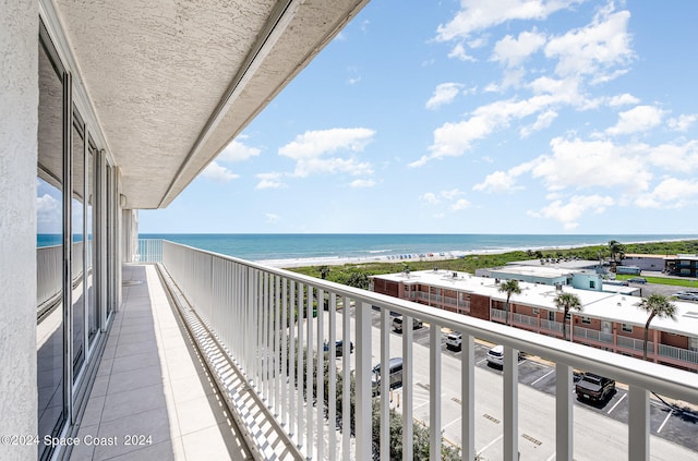 balcony with a water view and a view of the beach