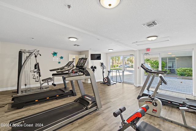 workout area with a textured ceiling and light wood-type flooring