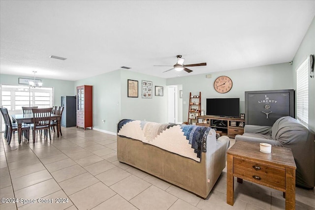 tiled living room featuring plenty of natural light and ceiling fan with notable chandelier