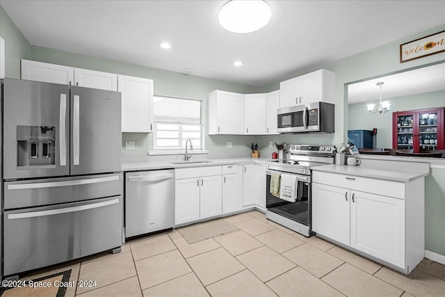 kitchen with pendant lighting, a notable chandelier, stainless steel appliances, kitchen peninsula, and sink