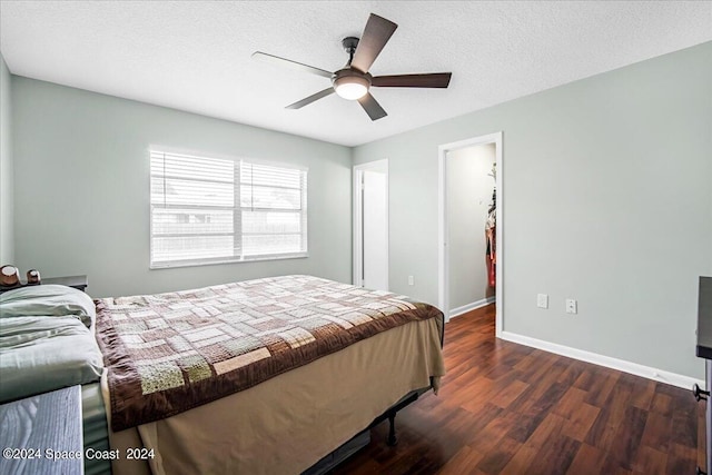 bedroom featuring a textured ceiling, ceiling fan, dark hardwood / wood-style floors, and a spacious closet