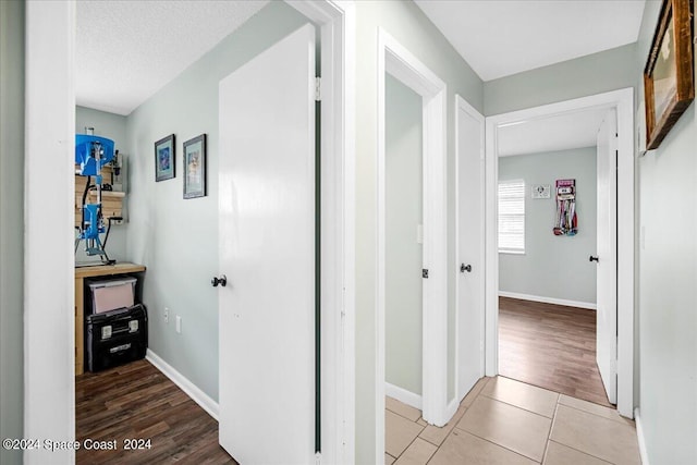 corridor featuring a textured ceiling and light hardwood / wood-style flooring