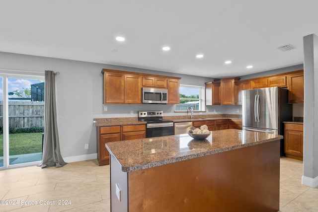 kitchen featuring dark stone counters, sink, a center island, appliances with stainless steel finishes, and light tile patterned flooring