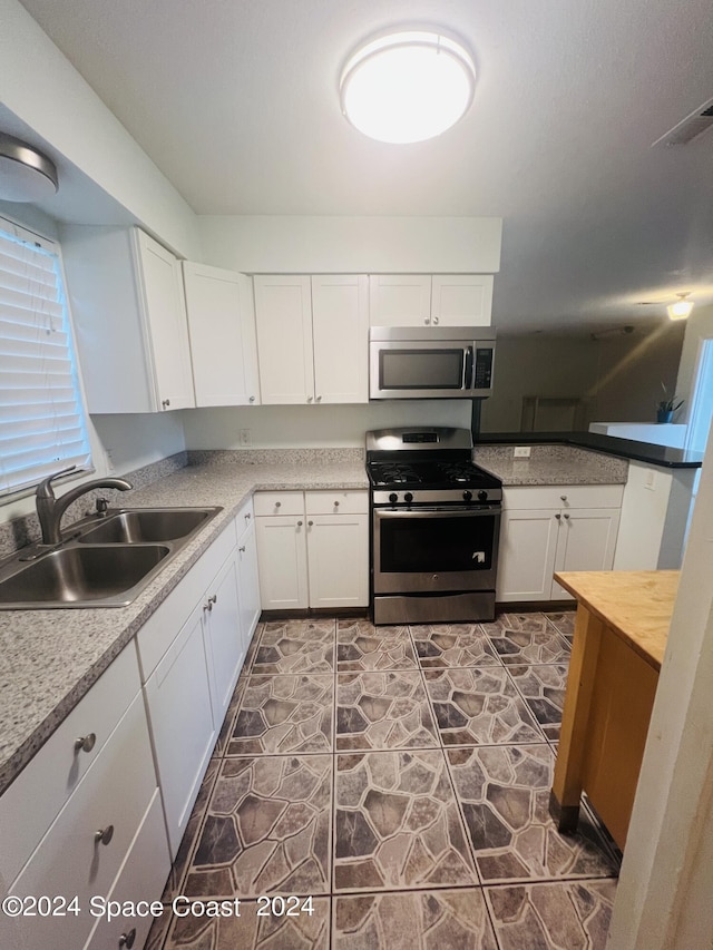 kitchen featuring visible vents, white cabinetry, stainless steel appliances, and a sink