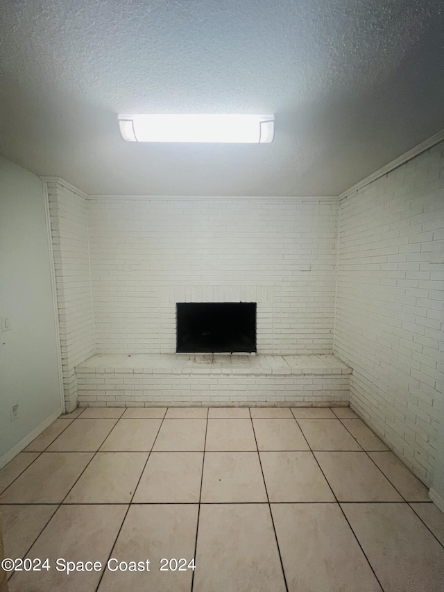 empty room featuring a textured ceiling, brick wall, and tile patterned floors