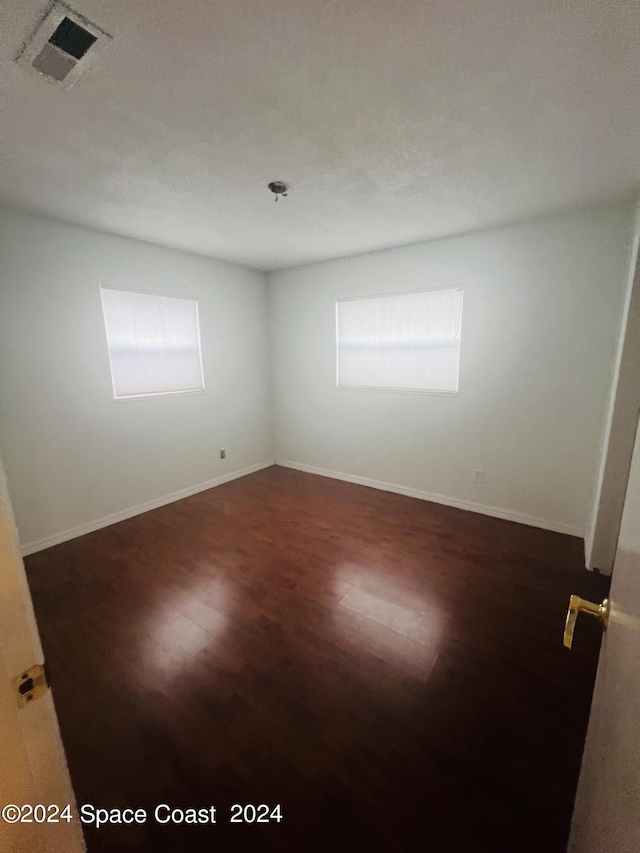 unfurnished room featuring visible vents, baseboards, and wood finished floors