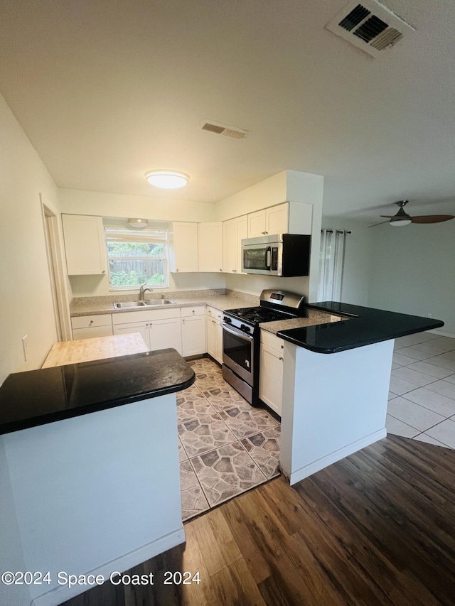 kitchen with stainless steel appliances, a peninsula, a sink, and visible vents