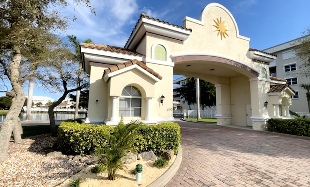 exterior space featuring decorative driveway, a tile roof, and stucco siding