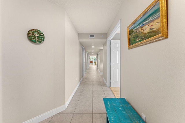 hall with light tile patterned floors, visible vents, and baseboards