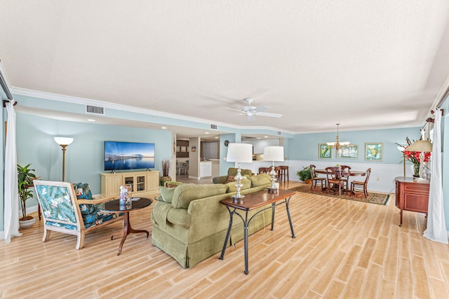 living room with visible vents, ornamental molding, a textured ceiling, light wood-type flooring, and ceiling fan with notable chandelier