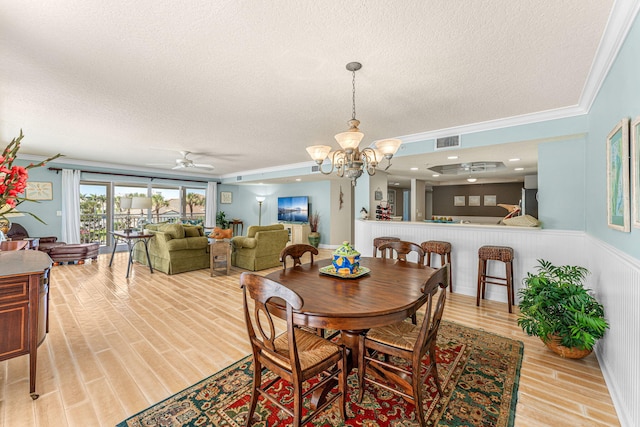 dining area with light wood-type flooring, crown molding, visible vents, and a textured ceiling