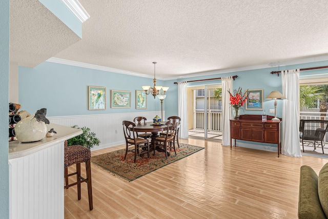 dining area with light wood-style floors, crown molding, a wealth of natural light, and wainscoting