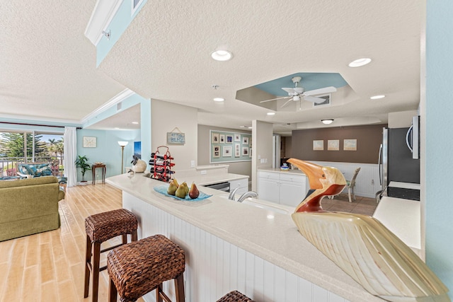 bar with a tray ceiling, stainless steel appliances, a textured ceiling, a sink, and recessed lighting