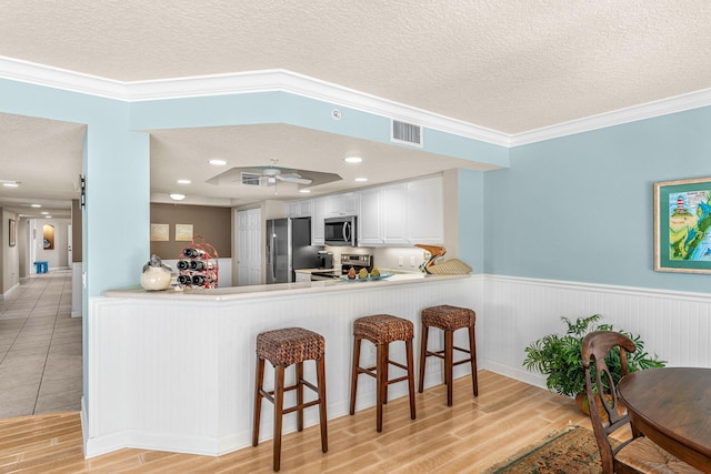 kitchen featuring a barn door, visible vents, a breakfast bar, stainless steel appliances, and a textured ceiling