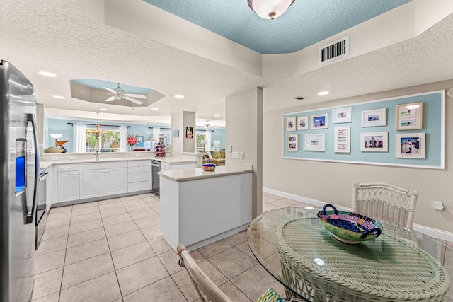 kitchen with visible vents, light countertops, appliances with stainless steel finishes, a sink, and a peninsula