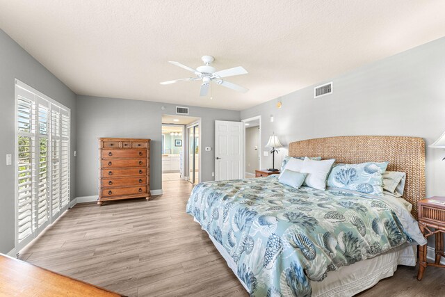 bedroom featuring access to outside, a textured ceiling, visible vents, and wood finished floors