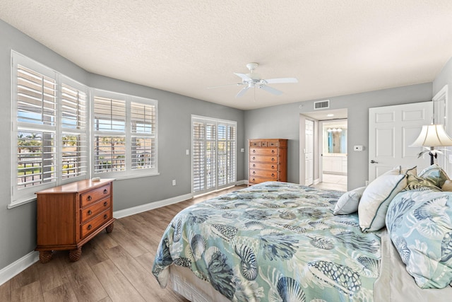 bedroom with a textured ceiling, wood finished floors, visible vents, baseboards, and access to exterior