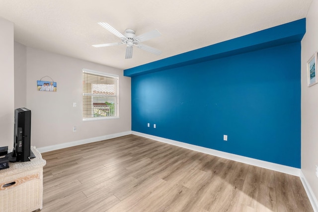 interior space with a ceiling fan, light wood-style flooring, and baseboards