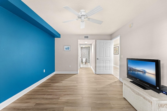 unfurnished living room with ceiling fan, wood finished floors, visible vents, and baseboards