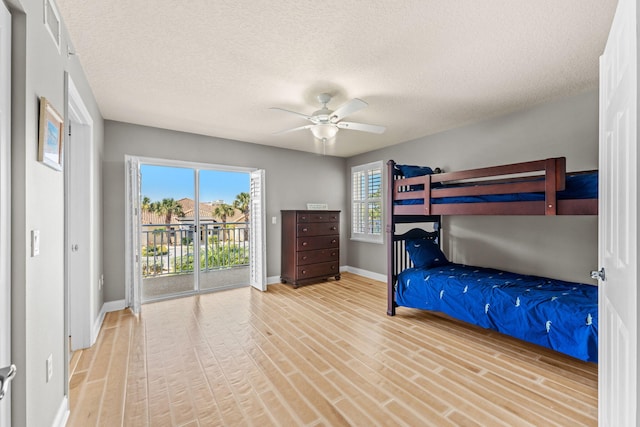 unfurnished bedroom with a textured ceiling, access to outside, wood finished floors, and baseboards