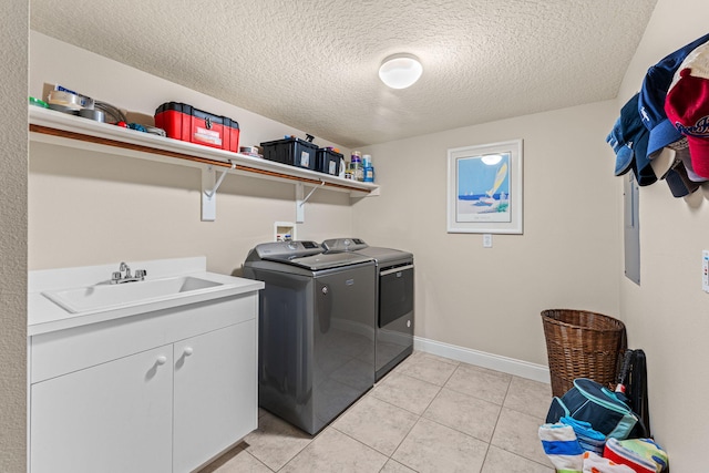 clothes washing area featuring light tile patterned floors, washing machine and dryer, a sink, baseboards, and cabinet space