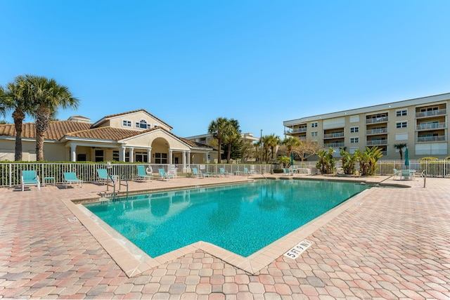 community pool with a patio and fence