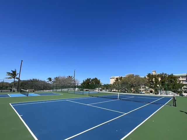 view of tennis court with community basketball court and fence