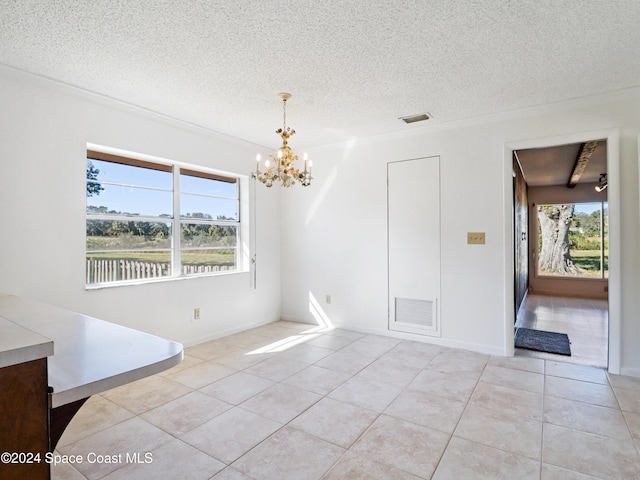 empty room with light tile patterned floors, a textured ceiling, an inviting chandelier, and a wealth of natural light