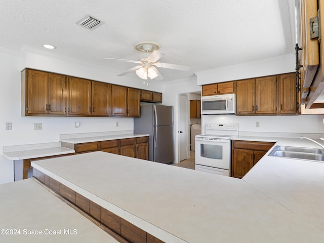 kitchen featuring white appliances, sink, ceiling fan, ornamental molding, and a textured ceiling