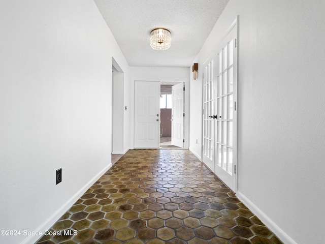 hallway with french doors and a chandelier