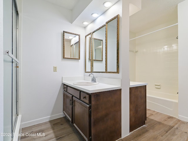 bathroom with hardwood / wood-style floors, vanity, and bathing tub / shower combination