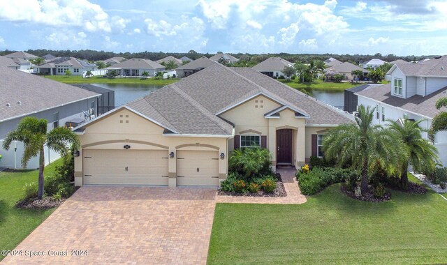 view of front of house featuring a garage, a water view, and a front lawn