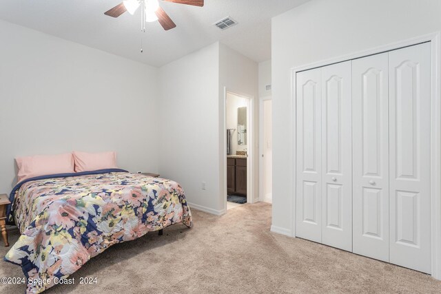 bedroom featuring ensuite bathroom, ceiling fan, light carpet, and a closet