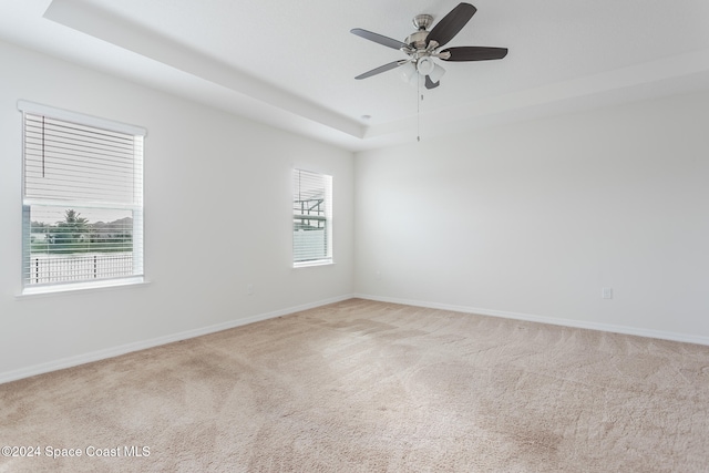 carpeted spare room featuring ceiling fan and a raised ceiling