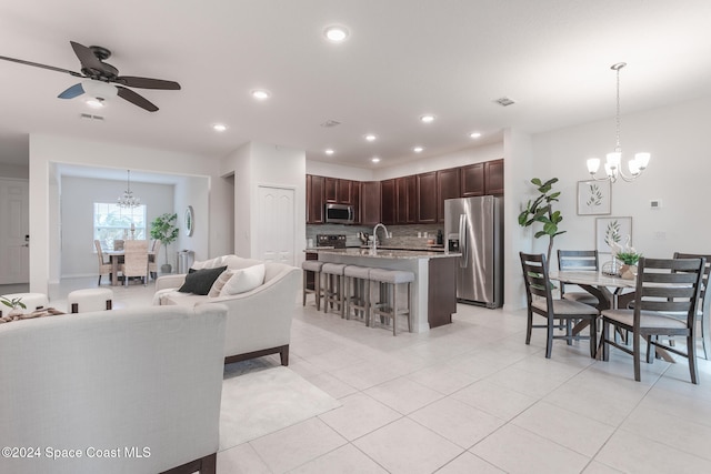 tiled living room featuring ceiling fan with notable chandelier