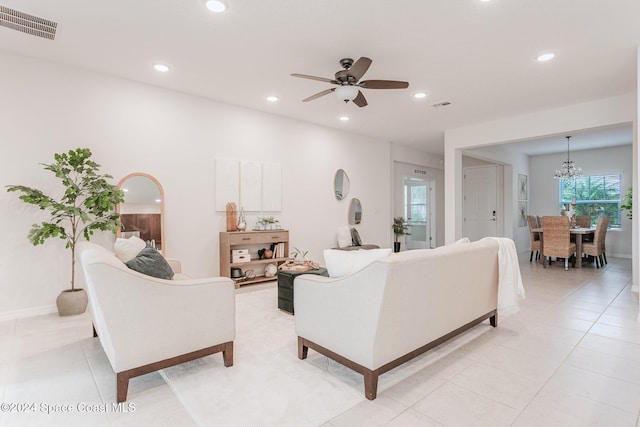 tiled living room featuring ceiling fan with notable chandelier