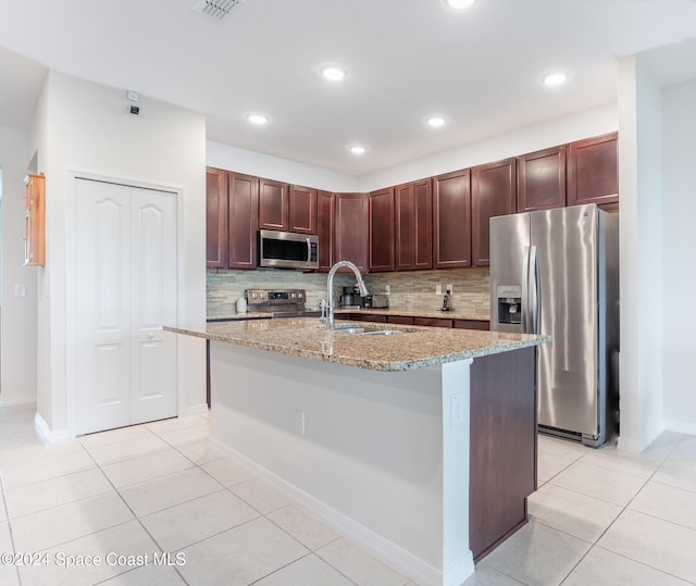 kitchen featuring stainless steel appliances, sink, backsplash, and light stone countertops