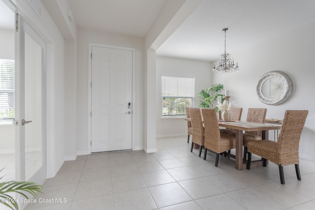 dining room featuring plenty of natural light, light tile patterned floors, and a chandelier