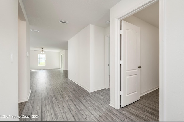 hallway featuring light wood-type flooring, baseboards, and visible vents