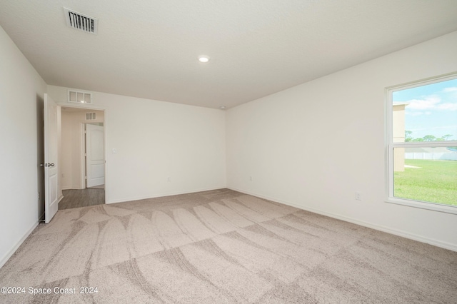 empty room featuring light colored carpet, visible vents, and baseboards